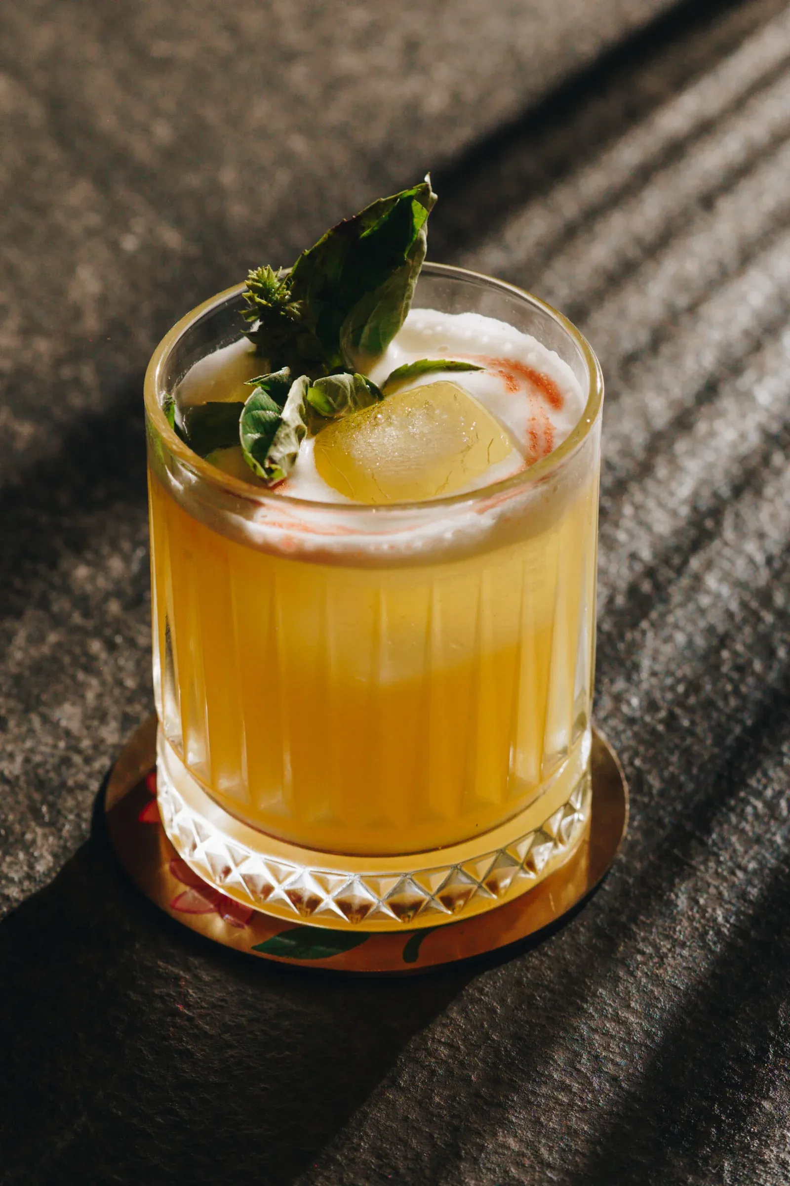 Purple Basil cocktail in a crystal rocks glass with a fresh herbal garnish